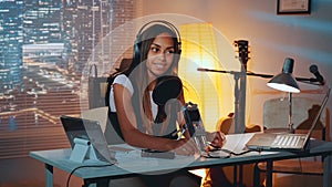 Multiracial female journalist doing online interview on the computer in home recording studio