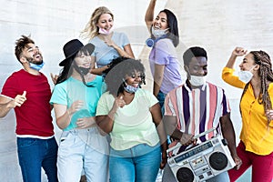 Multiracial friends dancing to music with boombox stereo outdoor with masks under chins - Focus on black man