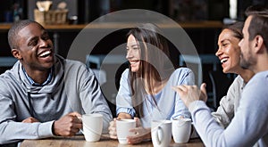 Multiracial friends girls and guys having fun laughing drinking coffee