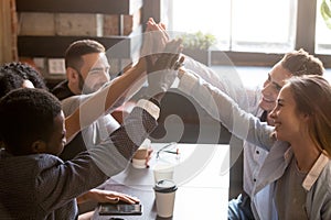 Multiracial friends giving high five sitting out in coffee shop