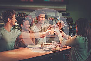 Multiracial friends having fun eating in pizzeria.