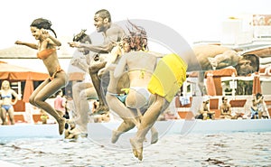 Multiracial friends having fun jumping at swimming pool party aquapark