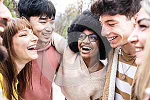 Multiracial friends hugging together outdoors - Happy young people enjoying day out walking outside