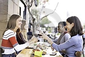 Multiracial friends toasting red wine at the outdoor pub in the city - Food and beverage lifestyle concept with happy people