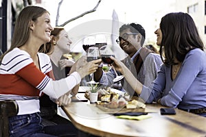 Multiracial friends toasting red wine at the outdoor pub - Food and beverage lifestyle concept with happy people having fun