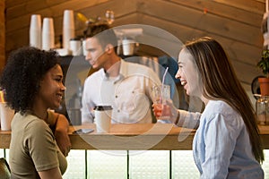 Multiracial girlfriends laughing, enjoying drinks at bar counter