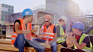 Multiracial group of diverse specialists at construction site have a lunch time together outside take some sandwiches to