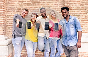 Multiracial group of friends showing blank smartphone screens outdoors - Young multi ethnic people having fun with mobile phones