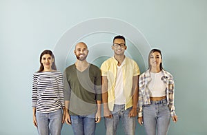 Multiracial group of happy, smiling young people standing against blue studio background