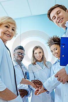 A multiracial group of medical interns in labcoats with clipboards and stethoscopes standing in a circle