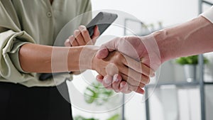 Multiracial group of young creative people in smart casual wear discussing business shaking hands together and smiling while