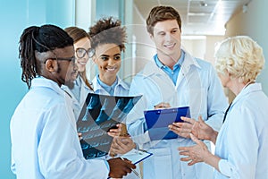 A multiracial group of young medical interns listening to a elder doctor in a