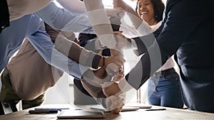 Multiracial happy affiliates stacked fists together involved in teambuilding activity