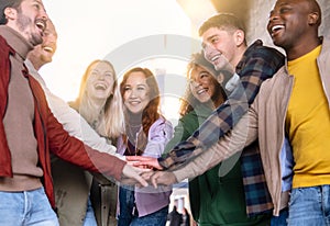 Multiracial happy friends with hands in stack