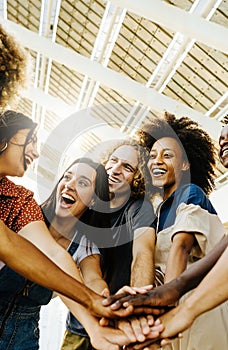 Multiracial happy friends with hands in stack