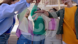 Multiracial happy friends stacking hands showing unity and support