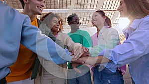 Multiracial happy friends stacking hands showing unity and support