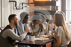 Multiracial happy young people laughing eating pizza together in photo