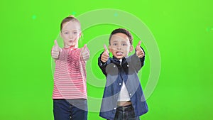 Multiracial kids friends showing thumbs up, while smiling to camera.