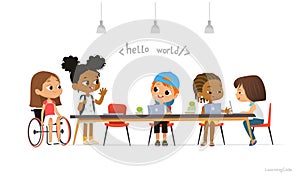 Multiracial kids sitting at laptops and learning coding during informatics lesson. Children greeting newcomer girl in a photo