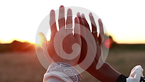 Multiracial love. black women and white man 's hands with golden rings touching outdoors in sunlight- slow motion