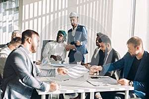 Multiracial male business executives discuss project sitting at conference table