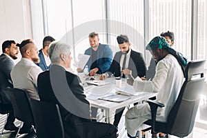 Multiracial male business executives discuss project sitting at conference table