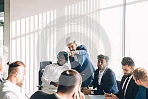 Multiracial male business executives discuss project sitting at conference table