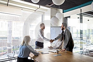 Multiracial male business partners handshake greeting at meeting photo