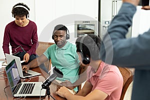 Multiracial male podcasters interviewing and recording podcast in creative office, copy space