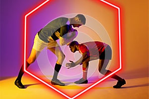 Multiracial male rugby opponents tackling ball by illuminated hexagon on gradient background