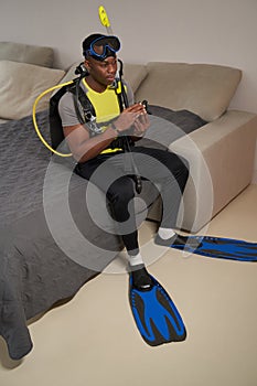 Multiracial man sitting on bed in scuba diving suit