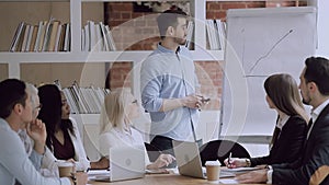 Multiracial mature and young employees listening to confident male speaker.