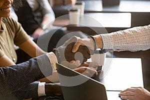 Multiracial men shaking hands in coffee house, close up view