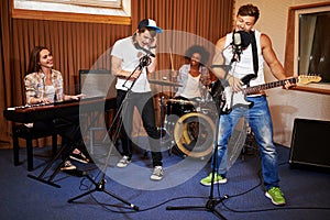 Multiracial music band performing in a recording studio