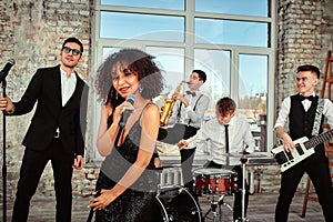 A multiracial music group performs in a recording studio. A group of international musicians rehearsing a concert