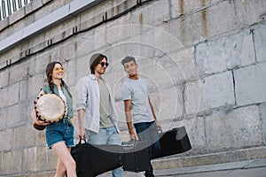 Multiracial musical band walking and carrying musical instruments on sunny