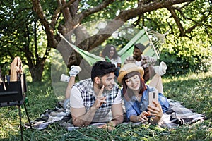 Multiracial peopel with mobile and drinks on picnic