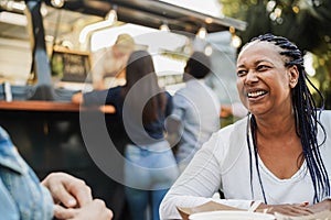 Multiracial people eating at food truck restaurant outdoor - Focus on african woman face