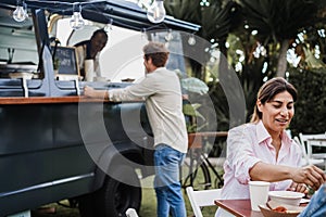 Multiracial people eating at food truck restaurant outdoor - Focus on hispanic woman face