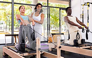 Multiracial people having pilates workout on reformers with trainer