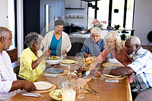Multiracial senior friends having lunch on dining table at nursing home
