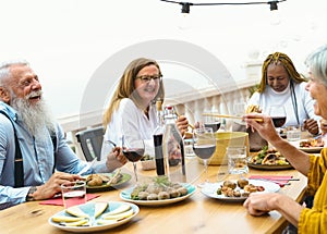 Multiracial seniors dining together at home terrace - Elderly people having fun at dinner on house patio