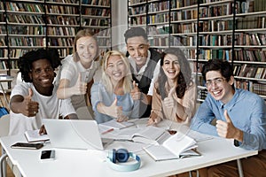 Multiracial students gather in library showing thumbs up at camera