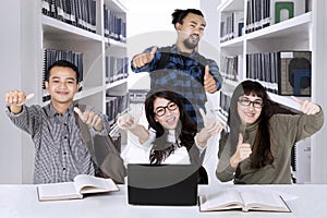 Multiracial students showing thumbs up in the library