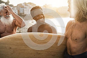 Multiracial surfer friends having fun on the beach after surf session - Main focus on faces