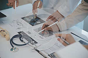 Multiracial team of doctors discussing a patient standing grouped in the foyer looking at a tablet computer, close up view