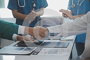 Multiracial team of doctors discussing a patient standing grouped in the foyer looking at a tablet computer, close up view
