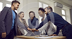 Multiracial team of happy young business people stacking hands after work meeting