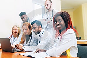 Multiracial team of young doctors working on laptop computer in medical office.